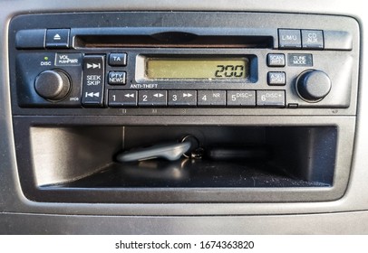 Grey Remote Control In A Pocket Below Old Fashioned Car Radio With CD Player.