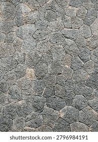 Grey rough stone wall texture background with irregular polygonal rock blocks