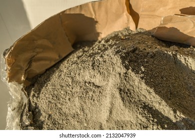 Grey sand-concrete dry mix in an open paper bag. Concrete dry powder for leveling walls and floors. Repair in the house with your own hands. DIY. Selective focus