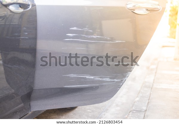 Grey Scratched car door with deep damage to the\
paint, damaged by\
accident.