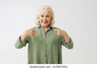 Grey Senior Woman In Shirt Smiling While Pointing Fingers At Herself Isolated Over White Background