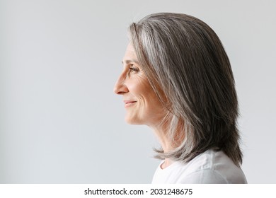 Grey senior woman in t-shirt smiling while posing in profile isolated over white background