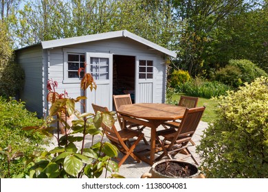 Grey shed with terrace and wooden garden furniture in a garden during spring