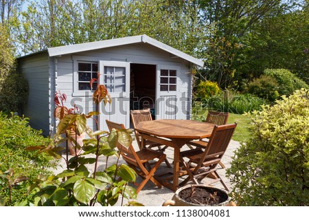 Grey shed with terrace and wooden garden furniture in a garden during spring