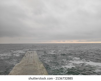 Grey Sky, Little Waves On The Sea Water And Seagulls On The Peer