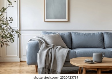 Grey sofa with a blanket, a pillow, a wooden coffee table and a plant on a wooden floor in a minimalist interior.