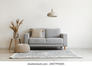 Grey sofa with cushion and pampas grass on coffee table in light living room