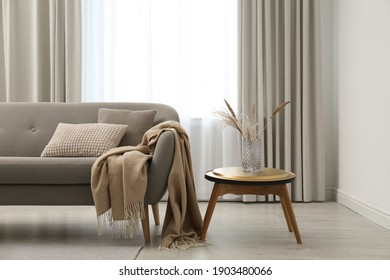 Grey sofa with pillows near window in stylish living room interior