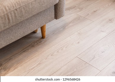 Grey sofa with wooden legs on lamonate floor - Shutterstock ID 1296568426
