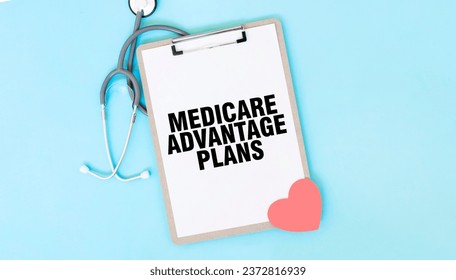 Grey stethoscope and paper plate with a sheet of white paper with text MEDICARE ADVANTAGE PLANS light blue background. Medical concept.