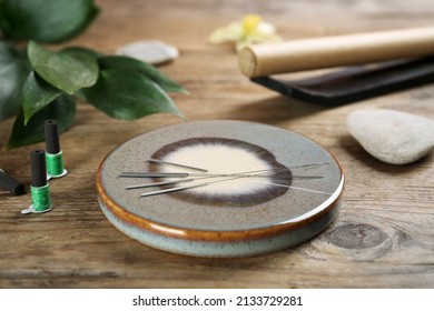 Grey Stone Coaster With Acupuncture Needles On Wooden Table