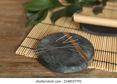 Grey Stone Coaster With Acupuncture Needles On Wooden Table