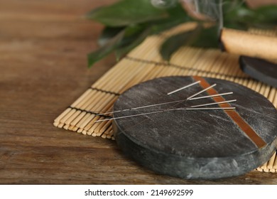 Grey Stone Coaster With Acupuncture Needles On Wooden Table. Space For Text