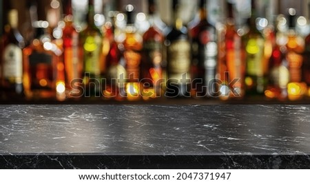 Grey table top and beautiful bokeh shelves with alcohol bottles at the background. Bar concept.