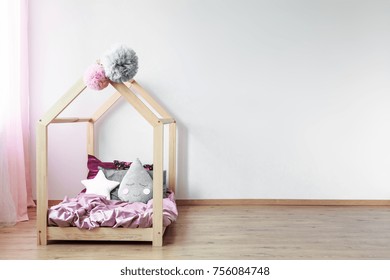 Grey Tear-shaped Pillow On Pink Satin Coverlet On Scandi Bed Against White Wall In Girl's Bedroom