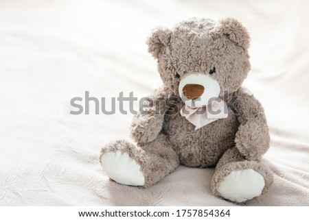 Grey toy teddy bear is sitting on the bed. Children toy.  Sadness and loneliness