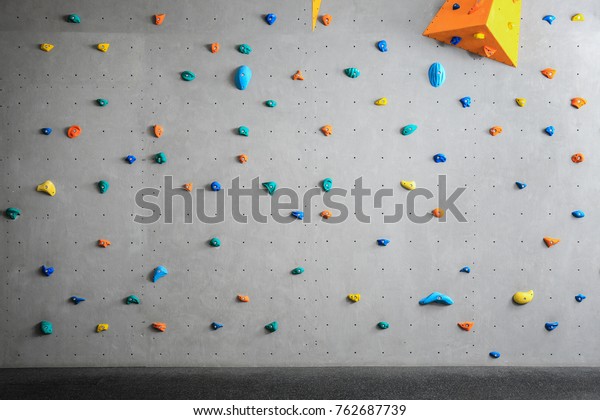 Grey wall with climbing\
holds in gym