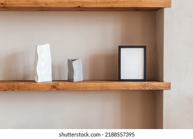 Grey And White Colored Vases, Blank Black Photoframe On Wooden Shelf Against Grey Wall. Home Decor.