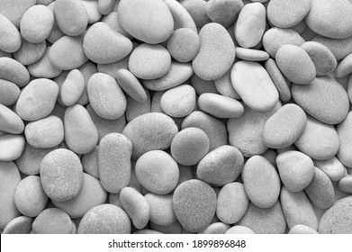 Grey and white stone background at the beach. Meditation concept during vacation. Round and smooth pebbles texture at daylight. Summer time near the sea. Cobblestone pattern. Rocks  at the seashore.