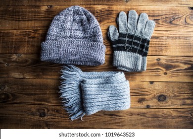 a grey winter hat gloves scarf on a wooden bacground