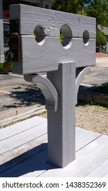 Grey Wooden Post With Pillory Or Stocks Used For Restraint Of A Person For Punishment And Public Humiliation