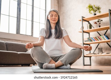 Grey-haired Mature Caucasian Woman Meditating At Home