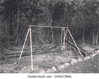 Greyscale photo of a swingset. Black & White, Woods, Creepy, Dark, Spooky.