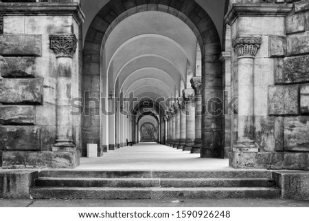 A greyscale shot of a concrete ancient building with a long hallway