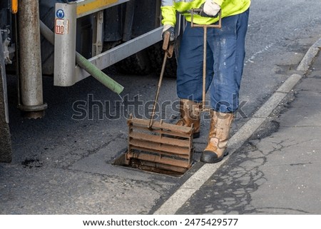 Grid Lifter tool or Cast Iron Gully Drain Cover Lifting Key Pair used to lift cast iron drain cover in suburban street.