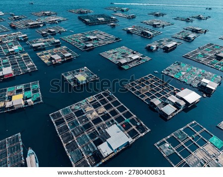 Grid pattern of floating fish cages across open sea in aerial drone view.