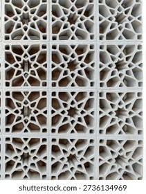 The grid pattern of Islamic architecture is known as the mashrabiya. A mashrabiya is a carved window element or latticework made of wood (or other materials such as concrete, as shown) commonly found in traditional Arabic architecture. The intricate designs also promote natural air circulation while blocking direct sunlight, helping to cool the building's interior in hot climates.
The visible geometric patterns are a hallmark of Islamic art, which often eschews figurative depictions.