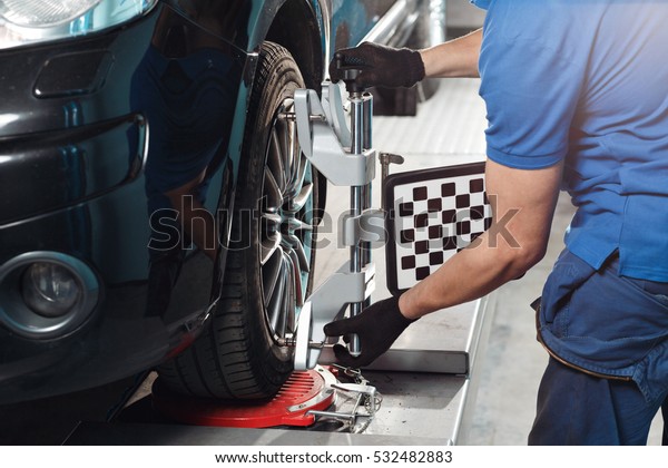 Grid sensor sets mechanic on auto. Car stand\
with sensors wheels for alignment camber check in workshop of\
Service station.