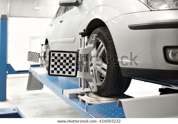 Grid sensor sets mechanic on auto. Car stand\
with sensors wheels for alignment camber check in workshop of\
Service station.