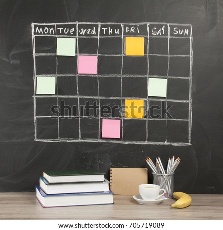 Grid timetable schedule with note paper on black chalkboard background