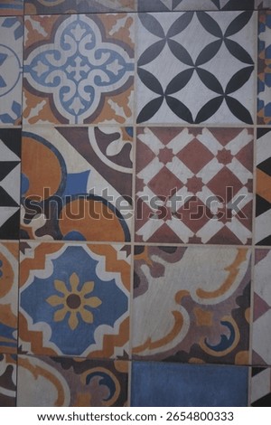 Grid of vibrant ceramic tiles featuring a mix of floral scrolls, symmetrical shapes, and abstract linework.