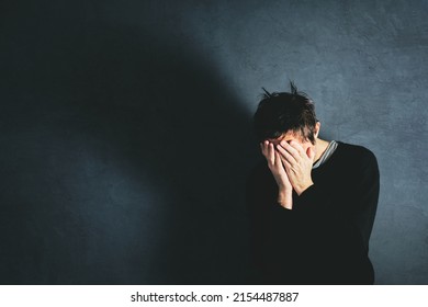 Grief concept, man coping with the loss in state of emotional distress, overwhelmed and helpless. Adult male covering face with his hands. - Shutterstock ID 2154487887