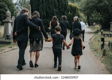 Grieving Family Walking Through A Cemetery