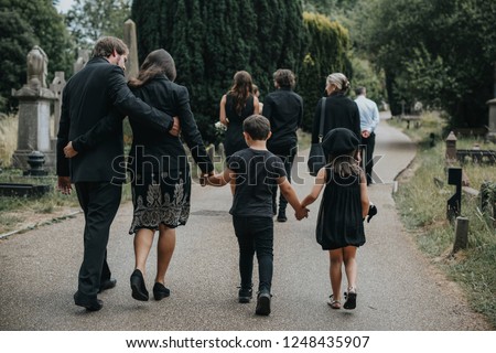 Grieving family walking through a cemetery
