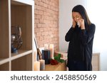 Grieving young Asian woman with mortuary urn crying at funeral