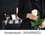 Grieving young woman with rose at funeral, closeup