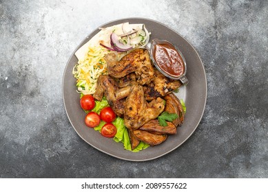 Griled Chiken Wings With Tomatoes And Green Letuce Salad, Cabbage Salad And Red Onion, Grilled Potatoes On The Plate.