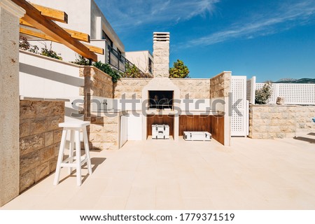 Grill area in the villa by the sea. A large courtyard with a stone grill and an open white stone kitchen.