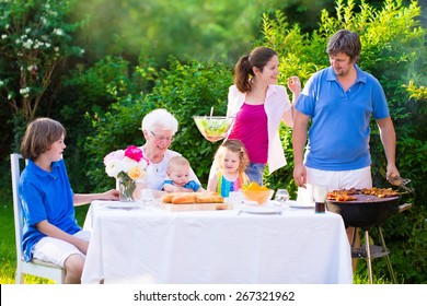 Grill Barbecue Backyard Party. Happy Big Family, Mother, Father, Teen Son, Cute Toddler Daughter And Little Baby, Enjoying BBQ Lunch With Grandmother Eating Meat In The Garden With Salad And Bread. 