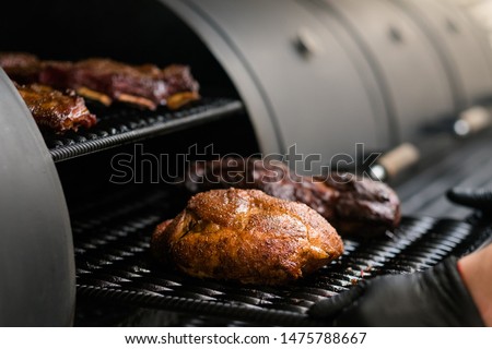 Grill restaurant kitchen. Chef cooking poultry, beef and pork meat, ribs in BBQ smoker.