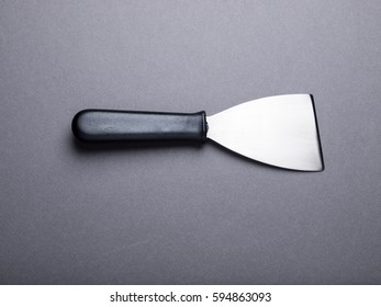 Grill Scraper With Black Handle Isolated On Dark Gray Background