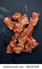 Grilled bacon with rosemary on blackboard.