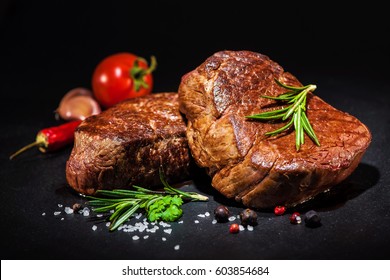 grilled beef fillet steaks with herbs and spices on dark background