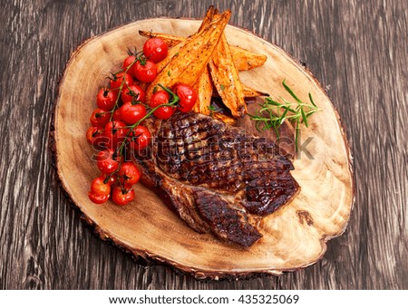 Grilled Beef Sirloin Steak on wooden board with vegetables.