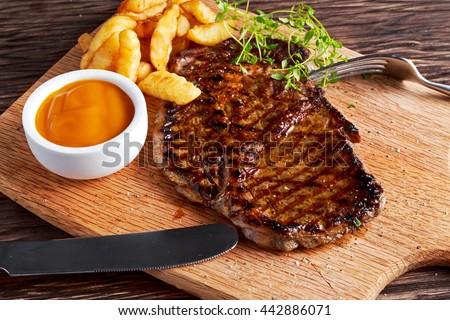 Grilled Beef Steak with Chips and Mango souce on wooden board.