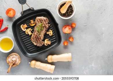 Grilled Beef Steak With Mushrooms And Spices On A Grill Pan On A Gray Background